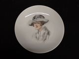 a white plate with a picture of a woman wearing a hat
