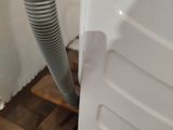 a white dishwasher sitting on a wooden pallet next to a wall