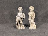 deux statues représentant un garçon et une fille tenant des fleurs, sur un fond gris