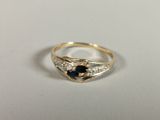 an image of a gold ring with a sapphire and diamonds