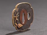 a gold and black brooch with a flower on it