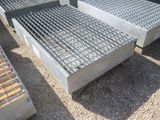 plusieurs grilles en acier sont empilées les unes sur les autres au sol