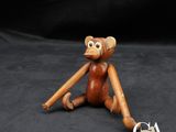 singe en bois assis par terre, une batte de baseball à la main