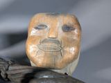 a wooden statue of a man with a face on a branch