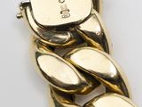 a close up of a gold bracelet with a chain attached to it