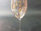 a wine glass with writing on it sitting on a table