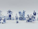 several blue and white figurines of people and animals on a white surface