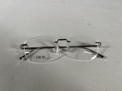 une paire de lunettes transparentes posée sur une surface blanche sur laquelle est inscrit le mot « Dior »