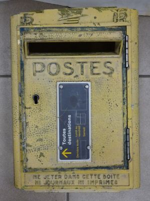 une boîte aux lettres jaune posée contre un mur