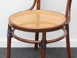 une chaise en bois avec une assise tressée, posée à même le sol