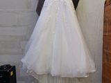 wedding dress hanging on a hanger in front of a brick wall