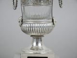 a silver vase with a rope handle on top of it
