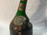 une vieille bouteille d'alcool posée sur une table blanche