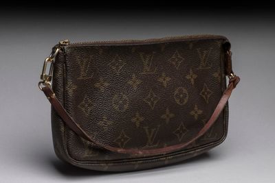 a louis vuitton cross body bag on a grey background