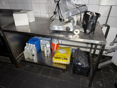 une table de travail en métal sur laquelle sont posées plusieurs bouteilles