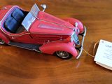 une petite voiture rouge posée sur une table en bois