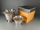 two silver cups sitting next to a box on a table