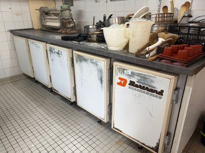 a dirty kitchen with a lot of clutter on the counter