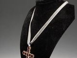 a close up of a necklace on a mannequin with a cross on it