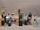 de nombreux flacons de parfum de styles variés posés sur une surface blanche