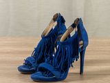 pair of blue high heels with fringes on a wooden surface