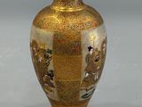 a gold vase with a picture on it on a gray surface