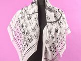 une écharpe blanche ornée de fleurs noires et roses, posée sur un mannequin