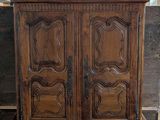a large wooden cabinet with two doors and a chandelier above it