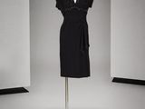 une robe noire posée sur un mannequin dans une pièce blanche