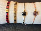 trois bracelets différents posés sur une serviette blanche, elle-même posée sur une surface en cuir noir