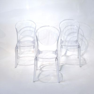 trois chaises en plastique transparent placées les unes à côté des autres sur une surface blanche