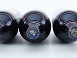 three bottles of wine are lined up on a white surface