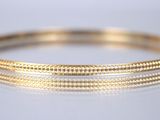 gros plan d'un bracelet en or sur une surface blanche