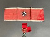 une image représentant un ruban rouge orné d'une croix et d'une médaille