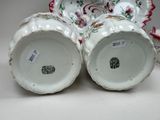 two white vases with floral designs on them sitting next to each other