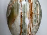 a green and brown marble egg on a white surface