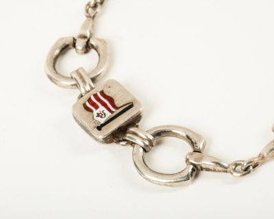 silver bracelet with a red and white flag charm on a chain
