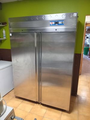 a stainless steel refrigerator in a kitchen with a green wall