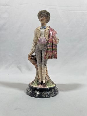 figurine of a boy with a hat and scarf holding a bag