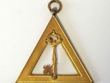 un triangle doré contenant une clé, sur un fond blanc
