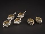 six cuillères en argent avec leurs repose-cuillères, posées sur un support noir