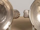 two silver bowls sitting on top of a wooden table