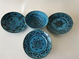 four blue bowls with designs on them sitting on a white surface