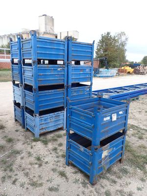 plusieurs caisses bleues empilées les unes sur les autres dans un champ