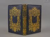 un vieux livre à la couverture dorée et bleue posé sur une table