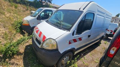 several white vans are parked in a grassy area next to a hill