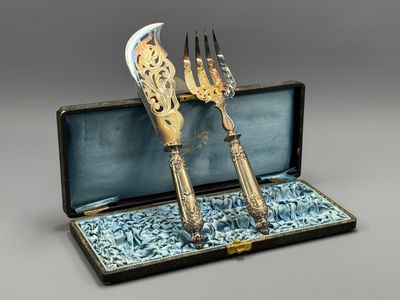 two forks and a knife in a case on a table