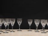 six empty wine glasses lined up on a table against a black background