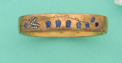 un gros plan d'une bague en or ornée d'oiseaux et de fleurs