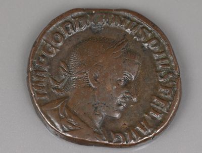 une vieille pièce de monnaie sur laquelle figure la tête d'un homme, sur un fond blanc